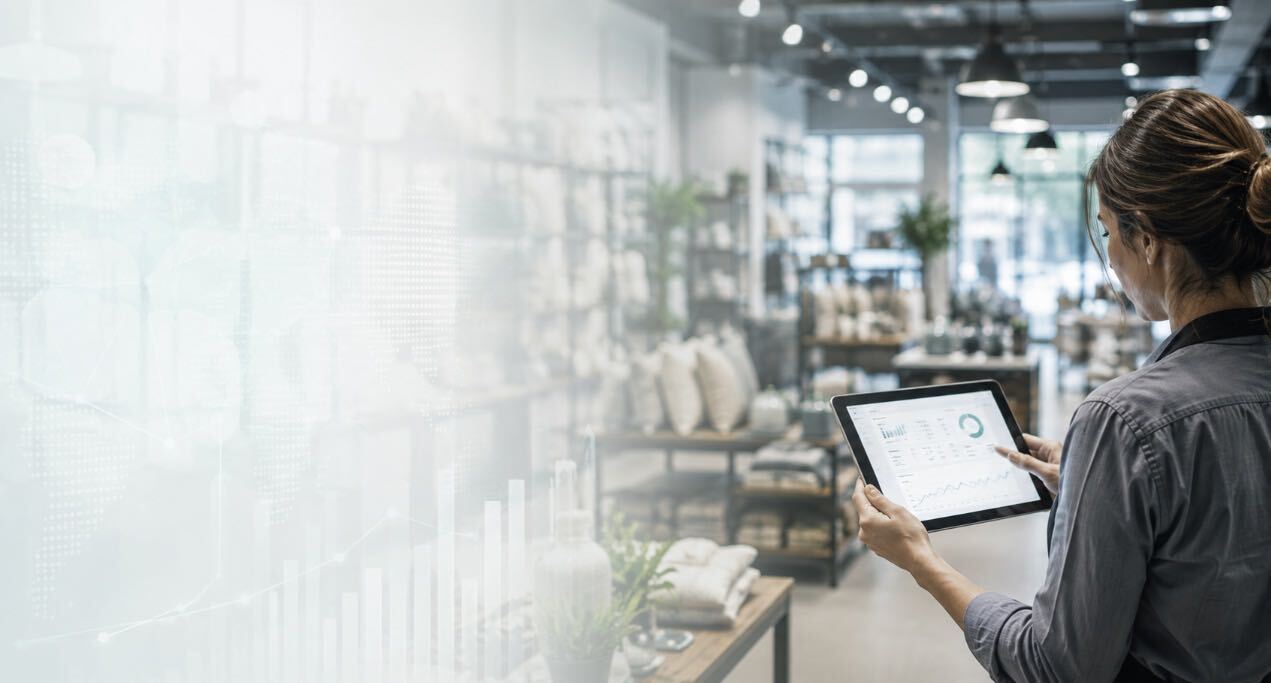 A woman is standing in a retail store looking at a tablet.